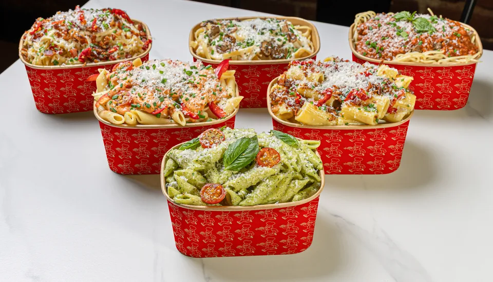 Les bols de pâtes Le Pastaman côte à côte sur le marbre : bolognaise, Alfredo, rosa, pesto et carbonara.